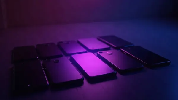 Diversi smartphone allineati, un faretto viola su quello centrale (illustrazione dell’articolo)
